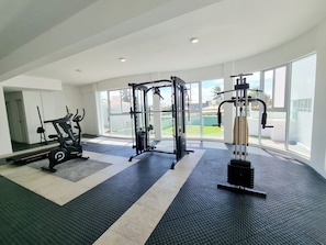 Une salle de sport équipée de machines de cardio, de bancs de musculation et dotée d’une grande fenêtre donnant sur l’extérieur.