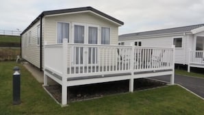 A mobile home with a fenced deck and a small porch. - Beechwood 18 -With Veranda -  No pets Allowed (Camber)