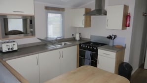 A compact kitchen with a toaster, sink, stove, and cabinets. - Beechwood 18 -With Veranda -  No pets Allowed (Camber)