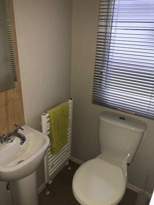 A bathroom with a white sink, toilet, and a window with blinds.