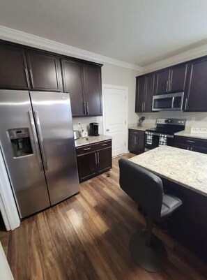 Enjoy cooking in this well-equipped kitchen with a refrigerator, microwave, and granite countertop.