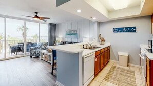 A modern kitchen with a central island, a dining area with a view, and a balcony with outdoor furniture. - Destin West - Sandpiper 407 (Okaloosa Island)