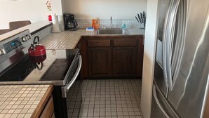 A compact kitchen with a stove, oven, sink, and stainless steel refrigerator. - Hilo's Finest 2 bd Condo - Pool, A/C, Views! (Hilo)