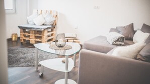 A modern living room with a glass coffee table, a sofa, and a wooden pallet bed. - Modern vacation apartment Knüllwald (Knüllwald)