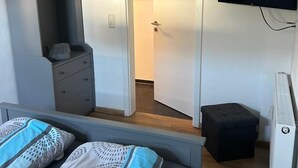 A bedroom with a bed, a dresser, a TV, and a heater. - Modern vacation apartment Knüllwald (Knüllwald)