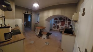 Una cocina compacta con cafetera, lavamanos y una mesa de madera.