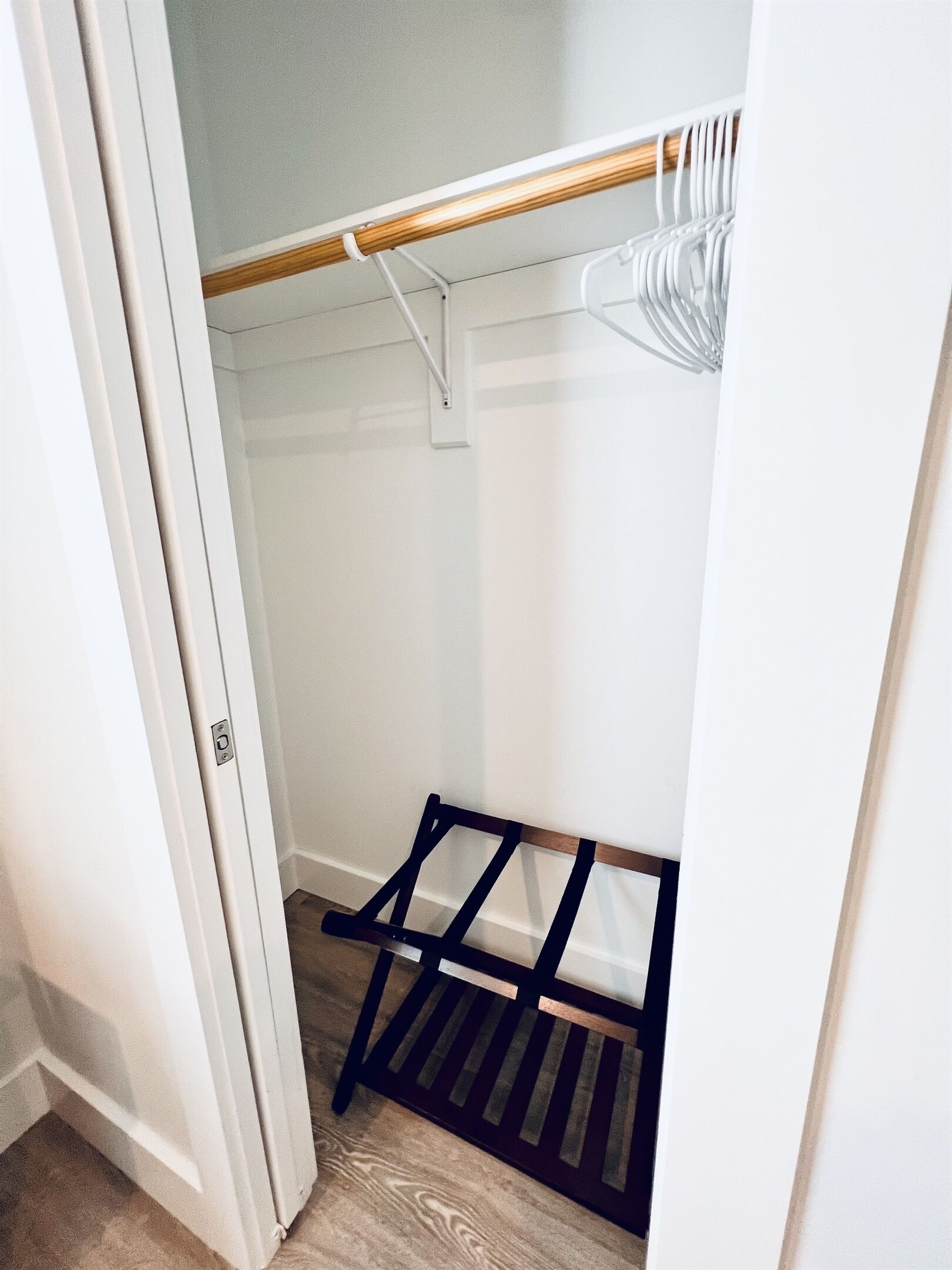 A closet with a wooden coat rack and a black hanging organizer.
