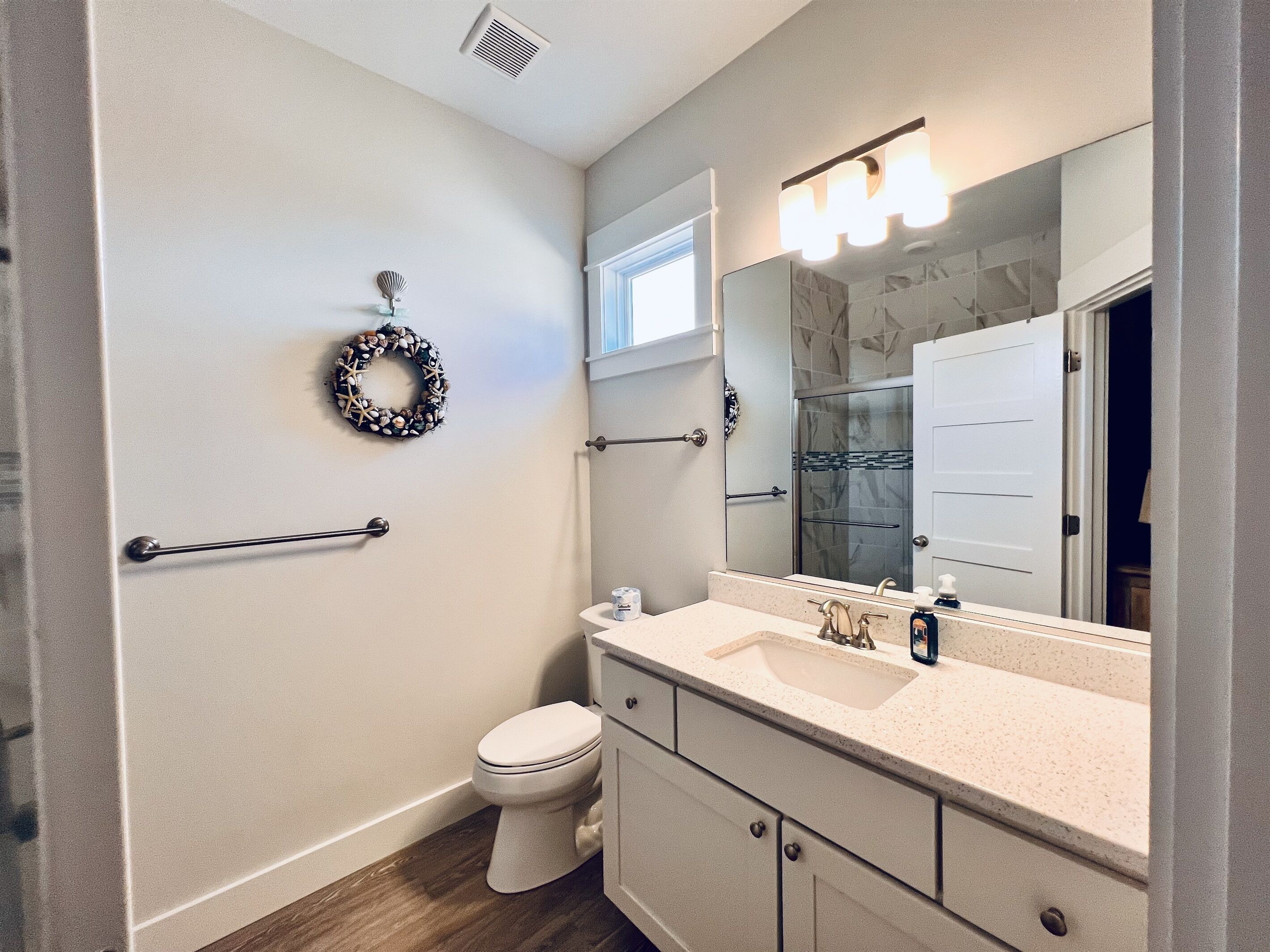 A bathroom with a toilet, vanity, mirror, and a towel rack.