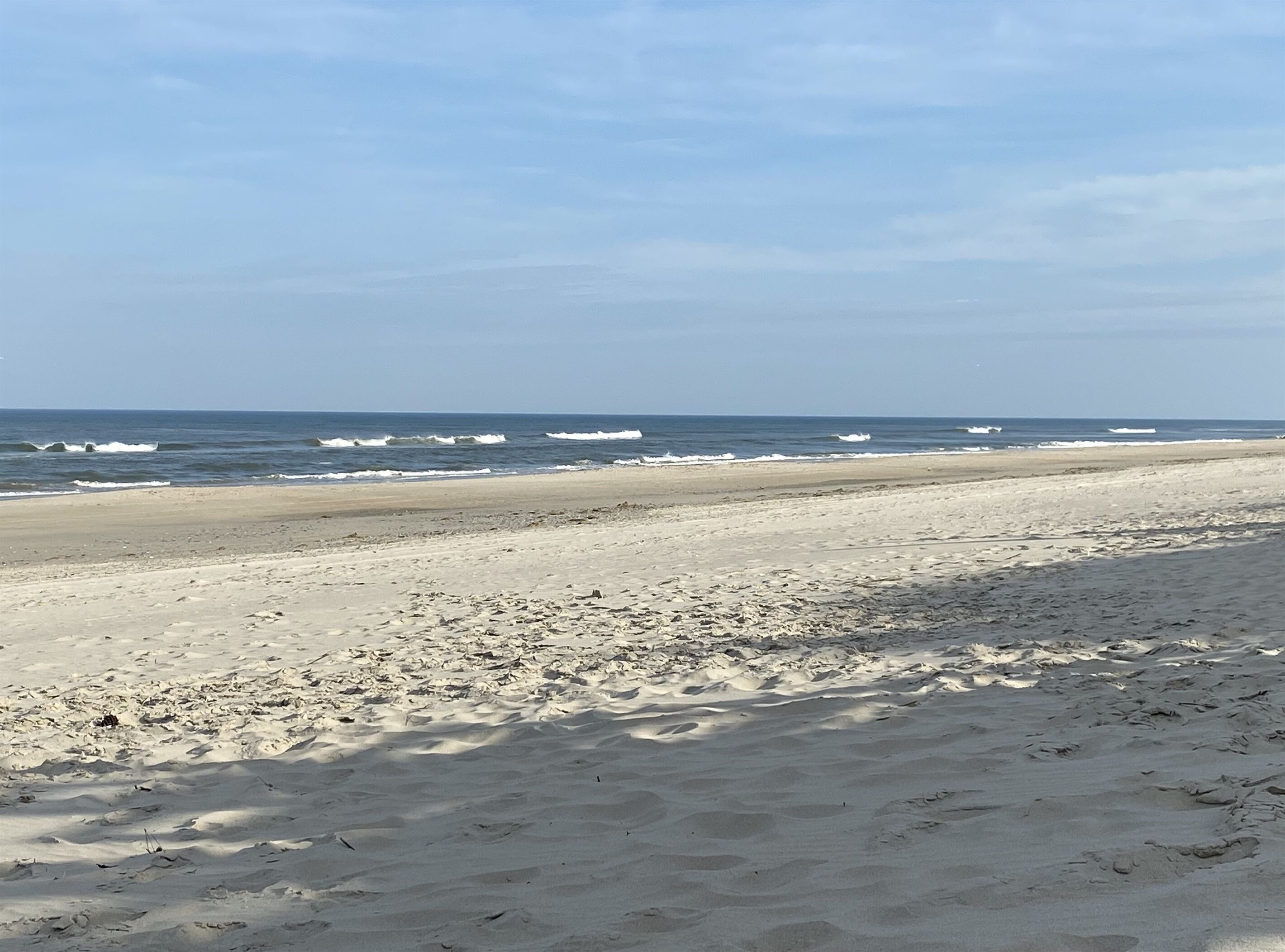 Een strand met een brede zandkust en golven in de oceaan.