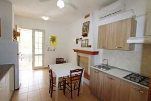 A kitchen with a dining table, chairs, a stove, and cabinets. - Myrtle House 1316 (Torre Pali)