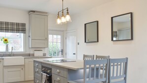 A modern kitchen with white cabinetry, a central island, a built-in oven, and a pendant light fixture. - 4 bedroom accommodation in Hinderwell (Hinderwell)