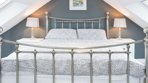 A bedroom with a metal bed frame, two bedside lamps, a framed picture on the wall, and a skylight. - 4 bedroom accommodation in Hinderwell (Hinderwell)