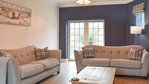 A living room with two sofas, a coffee table, a painting, and a ceiling light. - 4 bedroom accommodation in Hinderwell (Hinderwell)