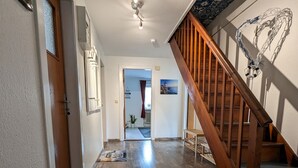 A hallway with wooden flooring, a staircase with wooden railings, and a ceiling fan. - Vacation apartment near the beach with sea view (Hohwacht (Ostsee))