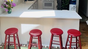 Une cuisine moderne dotée d’une verrière, d’un îlot central avec des tabourets, d’un réfrigérateur et d’un distributeur d’eau.