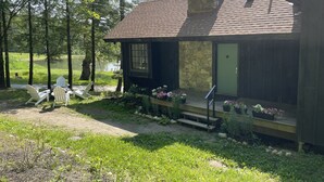 Un chalet rustique avec une cheminée en pierre, une véranda avec des marches et une vue sur un lac.