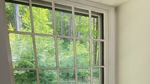 Un siège de fenêtre agrémenté de coussins, avec vue sur la verdure.