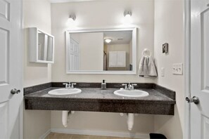 Une salle de bain avec deux lavabos, un grand miroir et une serviette accrochée au mur.