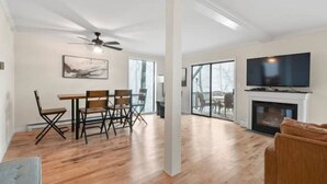 Un grand salon comprenant une table à manger, des chaises, une cheminée et un téléviseur.