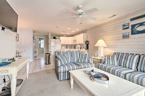 A modern living room with striped sofas, a white coffee table, and a ceiling fan.