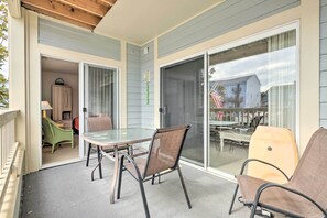 A covered patio with a glass door leading to a room, a table with chairs, and a view of a house through the glass. - Pool, Canal Views! Unit 1/2 Mi to Ocean City Beach (Ocean City)