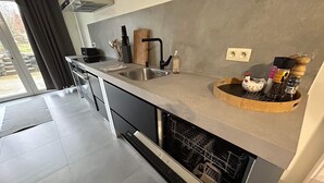 Una cucina moderna dotata di lavastoviglie, lavello e un tagliere in legno.