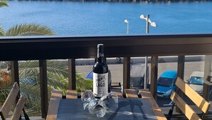 A balcony with a view of the ocean, a bottle of wine, and a glass. - Seafront San Andres (Santa Cruz de Tenerife)