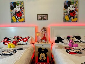 A bedroom with two beds, each adorned with Mickey Mouse-themed bedding.