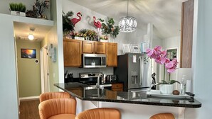 A modern kitchen with a central island, two bar stools, stainless steel appliances, and decorative plants. - Retreat Home W/ Heated Pool, 10 Min to The Beach (Melbourne)