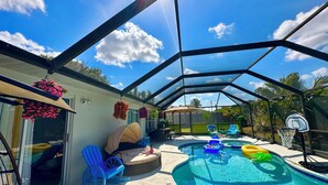 A covered outdoor swimming pool area with a basketball hoop, seating, and hanging flower baskets. - Retreat Home W/ Heated Pool, 10 Min to The Beach (Melbourne)