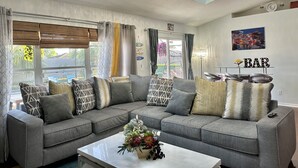 A modern living room with a sectional sofa, a coffee table, and a chandelier. - Retreat Home W/ Heated Pool, 10 Min to The Beach (Melbourne)