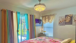 A bedroom with a floral bedspread, a television on the wall, and a window with curtains. - Retreat Home W/ Heated Pool, 10 Min to The Beach (Melbourne)