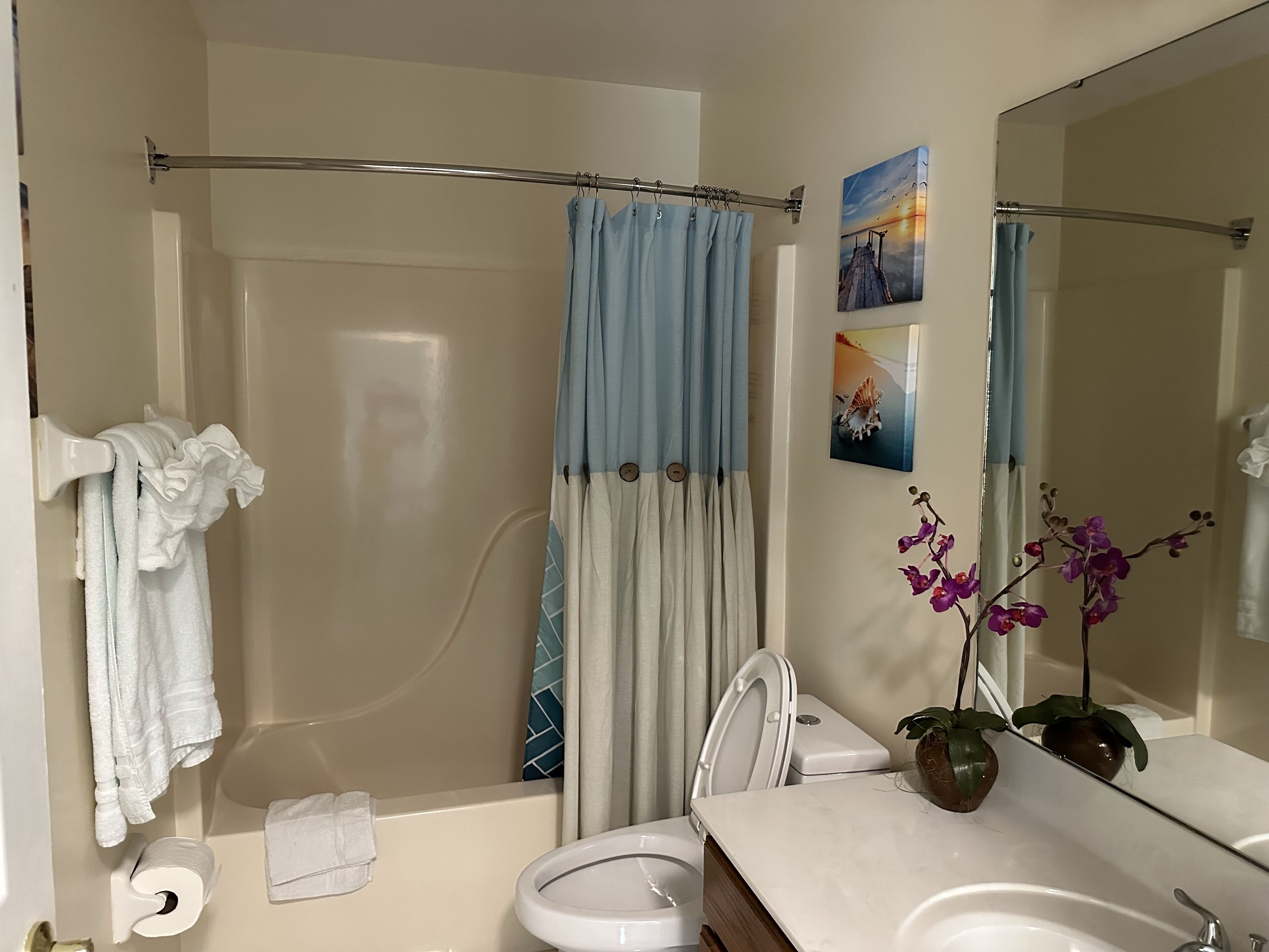 A bathroom with a bathtub, toilet, sink, and a shower curtain.