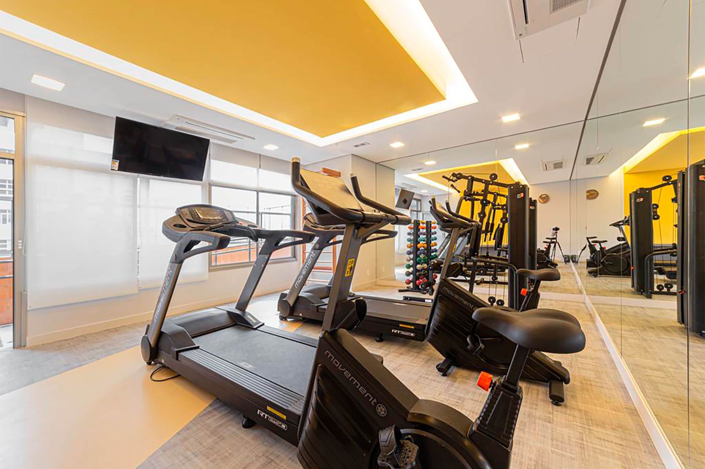 A modern gym with treadmills, stationary bikes, and weight machines.