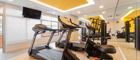 A modern gym with treadmills, stationary bikes, and weight machines.