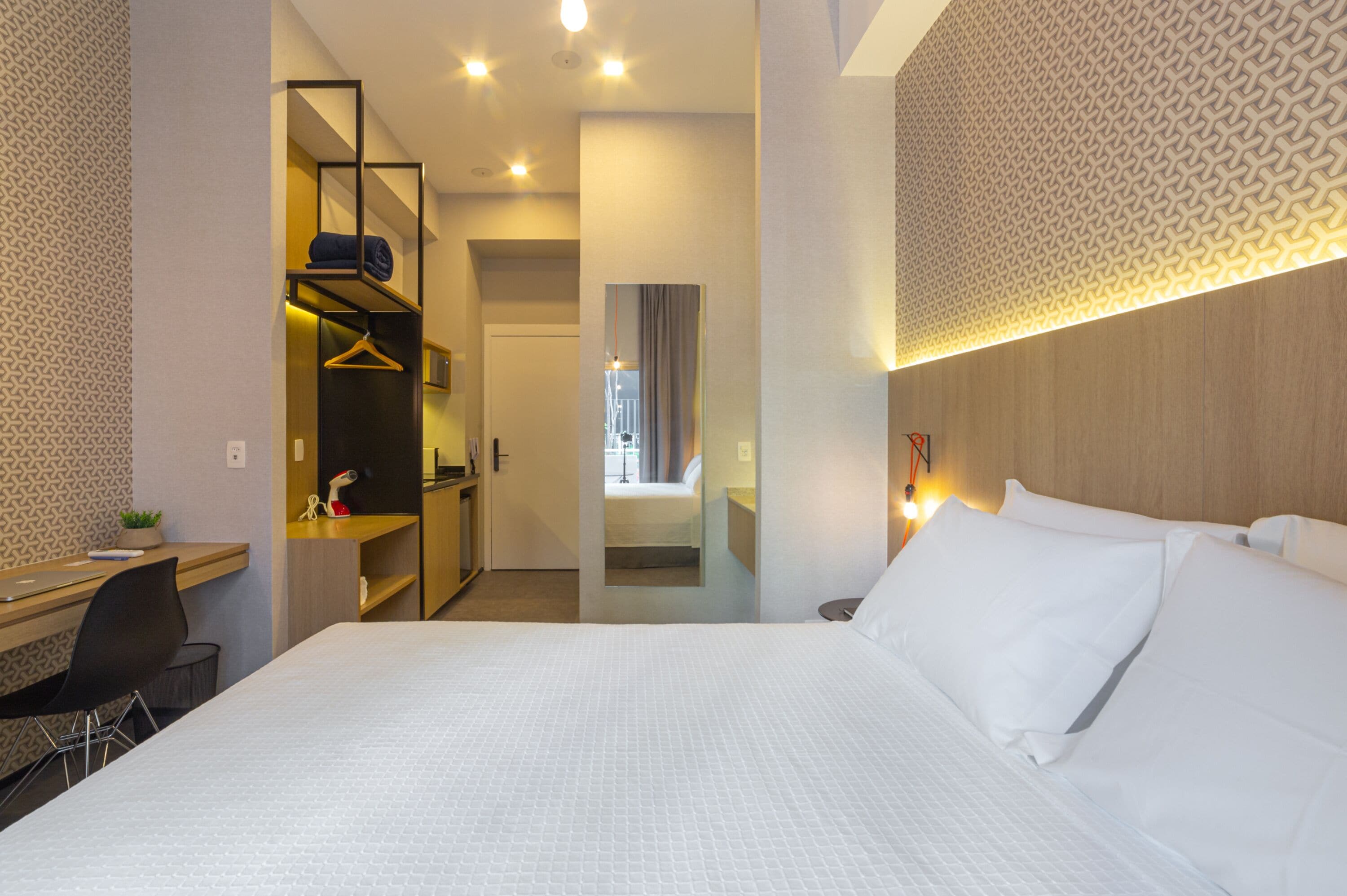 Una habitación de hotel con una cama grande, un escritorio, una silla y un armario.