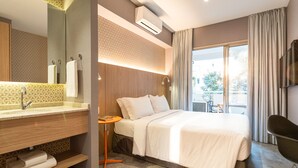 A hotel room with a large bed, a bathroom with a vanity, a small table, and a TV mounted on the wall. - Charlie Girassol Vila Madalena (São Paulo)