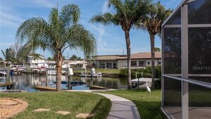A modern building with a glass facade, a landscaped area with palm trees, a pond, and boats. - Private Home in desirable Gulf Harbors neighborhood (New Port Richey)