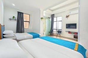 A hotel room with two beds, a desk, a chair, a TV, and a window with curtains.