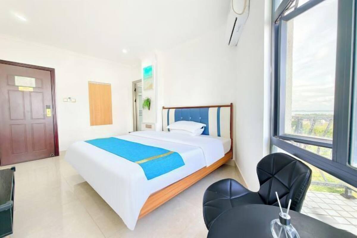 A hotel room with a bed, a desk, and a chair.