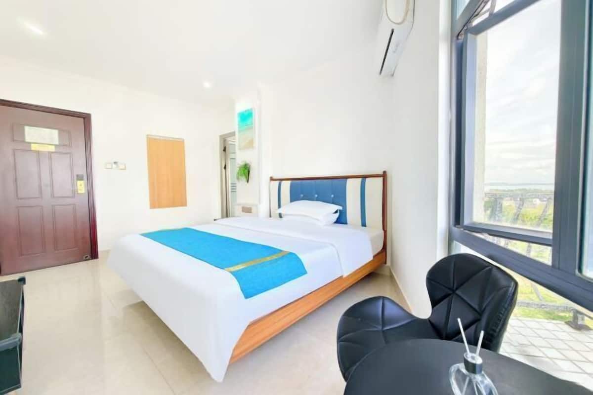 A hotel room with a bed, a desk, and a chair.