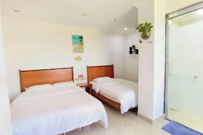 A hotel room with two single beds, a small bedside table with a lamp, a wall-mounted plant, and a beach-themed picture. - Yuehai Holiday Hotel (Shanwei)