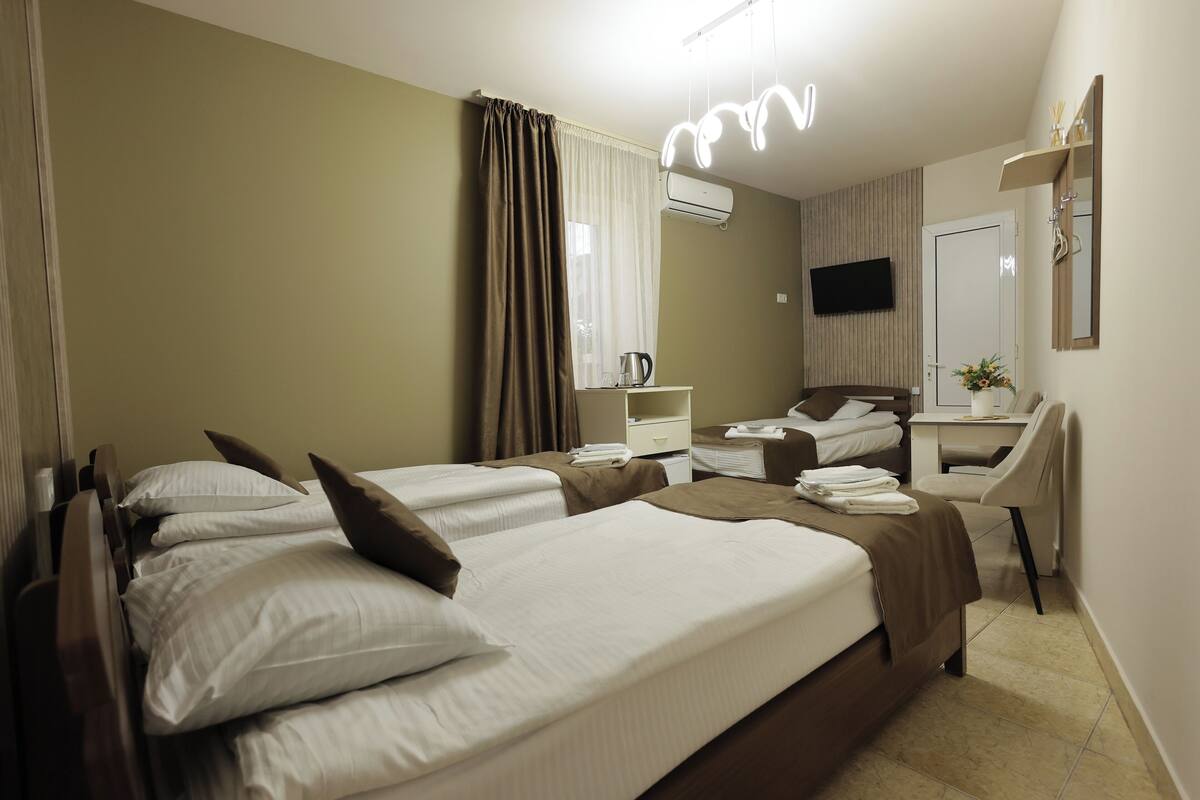 Habitación de hotel con dos camas, un escritorio, una silla, un televisor y un aire acondicionado.