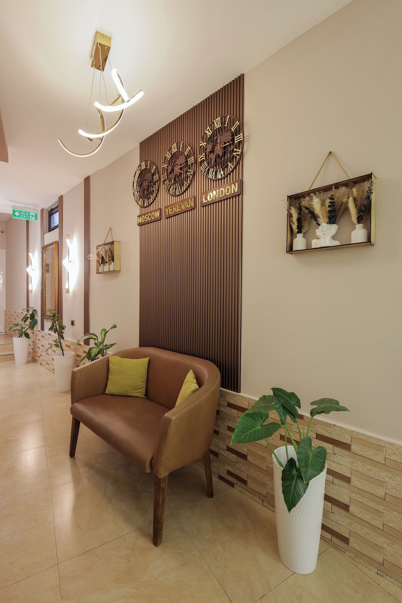 A reception area with a brown leather sofa, a potted plant, and wall clocks with city names.