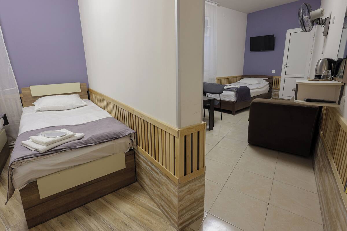 Habitación de hotel con cama, escritorio, silla, sofá, televisión y ventilador.
