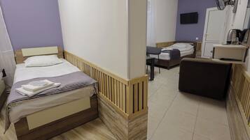 Habitación de hotel con cama, escritorio, silla, sofá, televisión y ventilador.