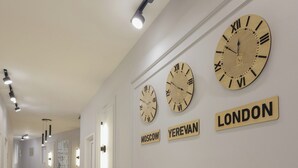 Um corredor com relógios, plantas em vasos e uma placa com a palavra 'LONDON'.