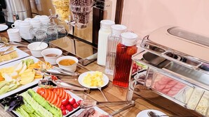 Buffet com diversas opções de comida, incluindo frutas, legumes, carnes e bebidas.