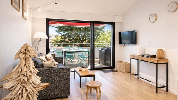 Una sala de estar moderna con un sofá, una mesa de centro y un televisor sobre un mueble.