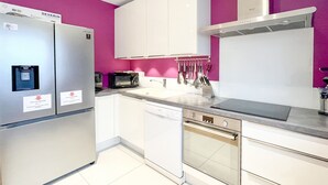 Una cocina moderna con armarios blancos, un refrigerador de acero inoxidable, un microondas y un lavamanos.